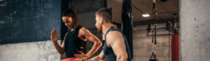 personal trainer entrenando chica fitness musculosa con tirantes negros